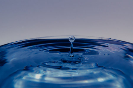 drop of blue water falling into a glass bowl