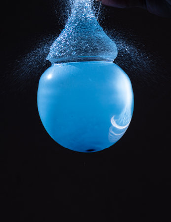 blue balloon filled with water bursting from aboveの写真素材