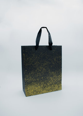 Black paper bag with golden dots textured on a white backgroundの写真素材