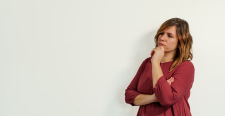 worried and pensive woman with her hand on her chin on a white background looking at the copy spaceの写真素材