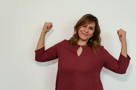 strong and empowered woman looking straight ahead and smiling on a white backgroundの写真素材