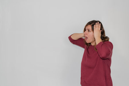 woman on a white background surprised with her hands on her head looking up at the copy spaceの写真素材