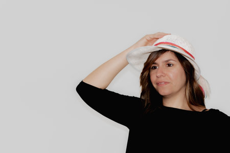 woman with a happy face holding the hat she is wearing on her headの写真素材