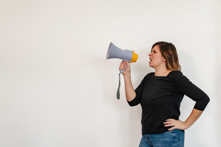 angry woman shouting into copy space with megaphoneの写真素材