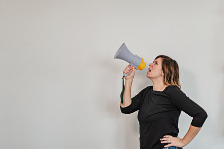 angry woman shouting upwards with a megaphoneの写真素材