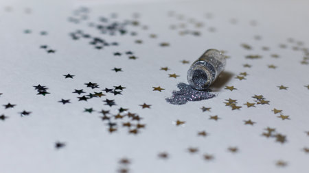 Transparent bottle with silver sparkles on a white background with silver stars. Magic backdrop with glitter. Minimalism concept for your design, advertising.の写真素材