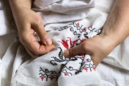 Seamstress's hands. Female hands with a needle, thread and thimble. Woman embroiders clothes. onceptual idea.の写真素材