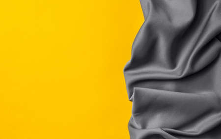 Bright trending yellow background with gray fabric. Top view. Minimalism concept. Perfect for presentations, decor and web design.の写真素材