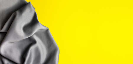 Bright trending yellow background with gray fabric. Top view. Minimalism concept. Perfect for presentations, decor and web design.の写真素材
