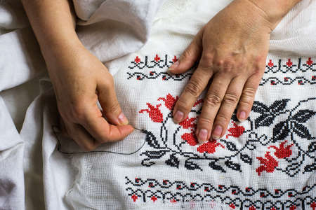 Seamstress hands. Female hands with a needle, thread and thimble. Woman embroiders clothes. onceptual idea.の写真素材