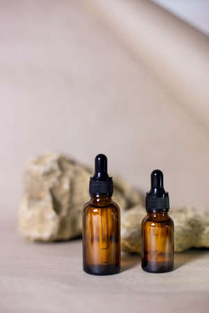 Dropper glass bottle mock up with dry flowers. Skincare brown bottle container on pastel pink background. Natural organic beauty product concept. Minimalism style. Flat lay, close up.の写真素材