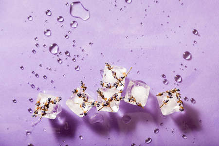 Melted pieces of ice on a purple background. Drip pattern. Top view.