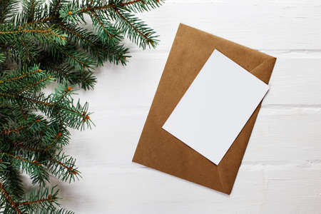 Spruce twigs and craft envelope on an wooden backdrop. Minimalist concept. Top view. New Year frame or Christmas mockup.の写真素材
