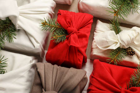 Christmas eco friendly gift wrapping in traditional Japanese Furoshiki style. Environmental present wrapping concept. Presents with green fir, pine cones, cinnamon and rose hips. Zero waste.の写真素材