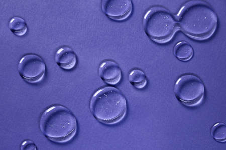 Cosmetic hydrating product or ingredient concept. Glowing blue drops of transparent liquid on a very...