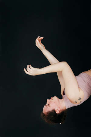 Close up studio portrait of a young brunette girl makes smooth movements with her hands. Concept for...