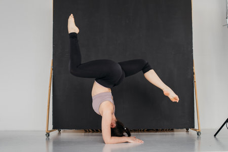 Young professional gymnast woman standing on splits. Pretty brunette girl doing an elbow stand....