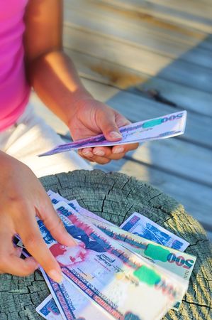 Happy girl holding currency in hand and counting moneyの写真素材