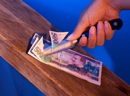A woman is cutting with a knife into Money. Lempiras, Honduras on wooden underground with blue backgroundの写真素材