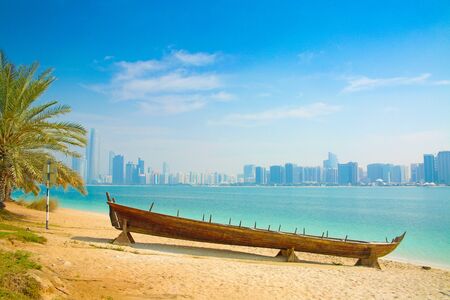 Modern arabic City of Abu Dhabi.  Landscape and cityscape panorama with wooden boat in the forground...