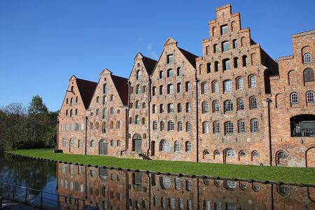 Six historic brick buildings that were used as salt storehouses on the Upper Trave River next to the Holstentor (the western city gate) of Lubeck, Germany.の写真素材