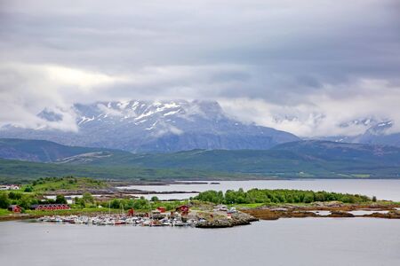 Beautiful landscape along with waters edge, with a village & church & mountains in the background, Saltstraumen, Municipality of Bodo, Nordland county, Norway.の写真素材