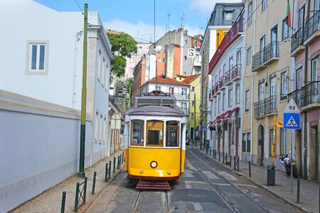 Historic yellow tram against old town streets, part of the tramway network since 1873, Lisbon, capital city of Portugal.の写真素材