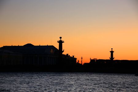 The Rostral Columns and the Old Saint Petersburg Stock Exchange buildings in silhouette at sunset, which are situated on Strelka, the eastern tip of Vasilievsky island, St Petersburg, Russia.の写真素材