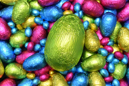 Pile or group of multi colored and different sizes of colourful foil wrapped chocolate easter eggs...