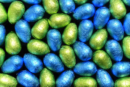 Pile or group of multi colored and different sizes of colourful foil wrapped chocolate easter eggs...