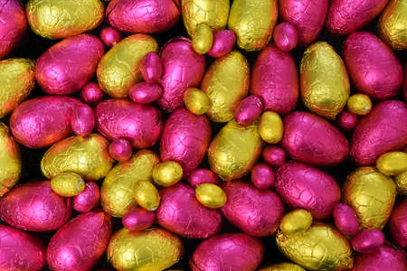 Pile or group of multi colored and different sizes of colourful foil wrapped chocolate easter eggs...