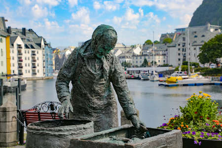 Sildekona (Herring Woman or Fish Lady) Statue with one of the canals with boats and art nouveau buildings in the background, Alesund, Norway.のeditorial素材