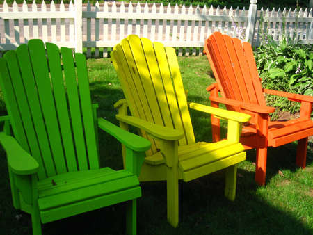 colourful adirondac chairs with picket fence in the back groundの写真素材