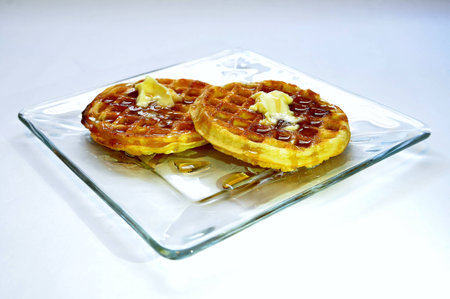 Waffles with melted butter and maple syrup on glass plateの写真素材