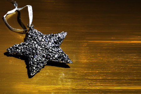Silver Christmas star ornament on a golden backgroundの写真素材