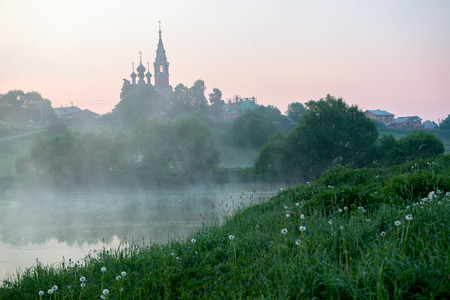Early morning sunrise village in Russia. Landscape with a church at the hill topの写真素材