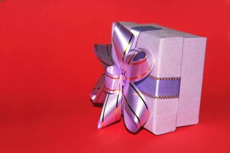 A gift with a beautiful ribbon isolated on red backgroundの写真素材