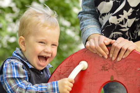 boy laughing on the swingの写真素材