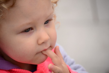 girl holding a finger in the mouthの写真素材