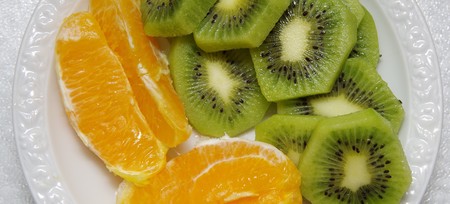 slices of kiwi and orange on a white plateの写真素材