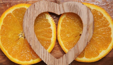 two slices of orange with wooden heartの写真素材