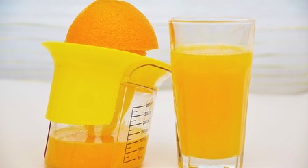 freshly squeezed orange juice in a glass and squeezer
