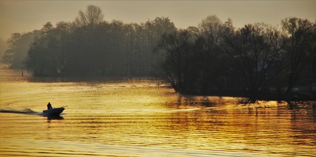 Boat with fisherman on the river at dawnの写真素材
