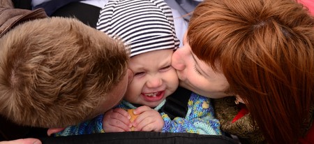 parents kiss the baby on bothsidesの写真素材