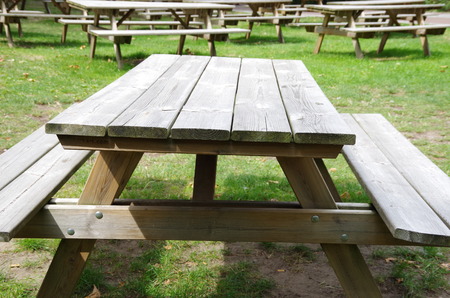 wooden unpainted table with benches stands outdoors
