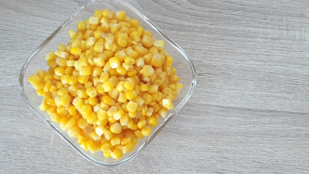 corn kernels in a glass cup on a wooden tableの写真素材