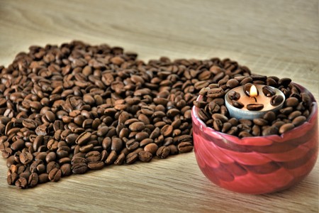 Silhouette of the heart of coffee beans and a candle with a burning wickの写真素材