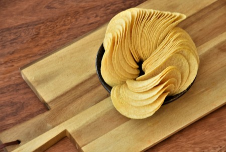 fried potato chips in a black bowl on a wooden board