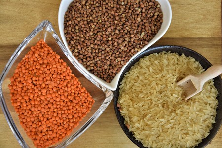 Raw lentils, rice and buckwheat on a wooden board