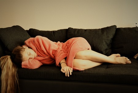 Girl with long hair in a pink robe asleep on the couch